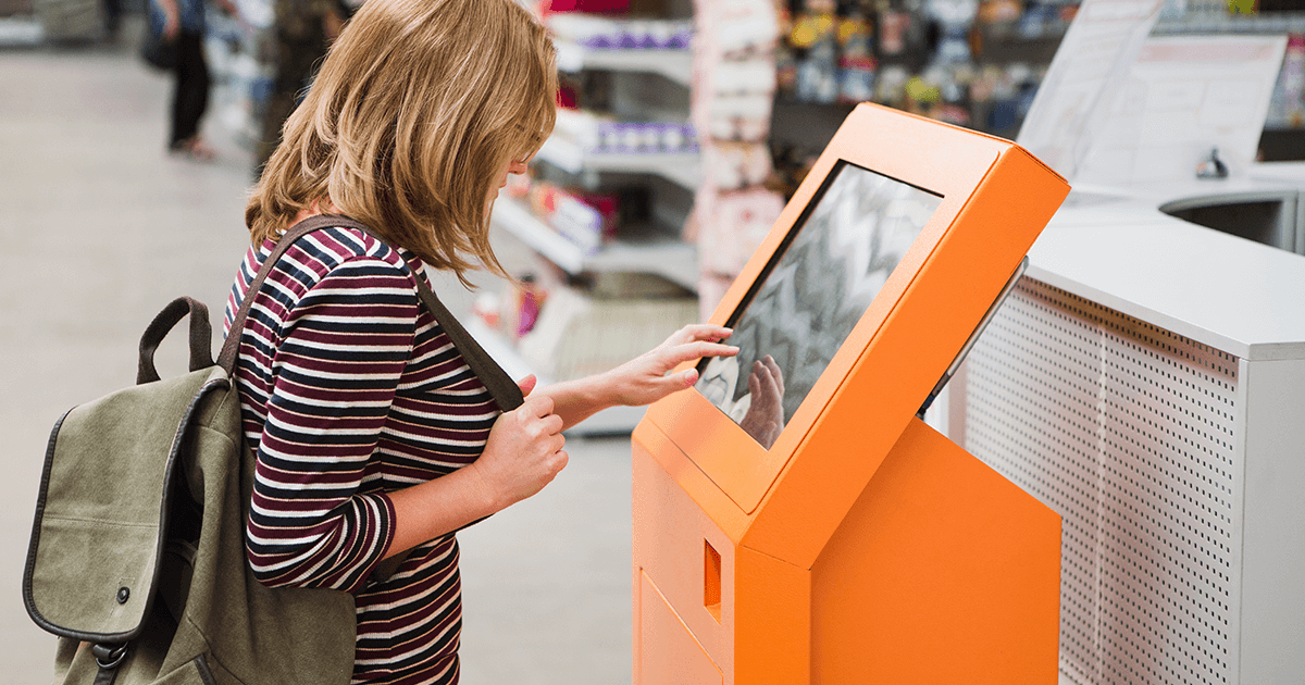 Woman using self-service kiosk while shopping 